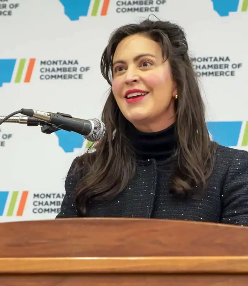Christi Jacobsen, with long dark hair, smiles as she speaks at a podium in front of a backdrop featuring the Montana Chamber of Commerce logo during Business Days.