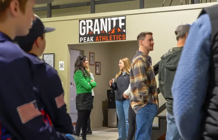 Secretary of State Christi Jacobsen honors Montana small businesses during National Small Business Month 5 A group of people stands and talks inside a building near a Granite Peak Athletics sign. Two women stand near the doorway while others, including people in blue uniforms, converse nearby during National Small Business Month.