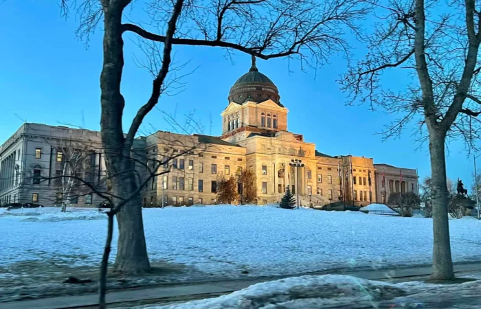 Secretary Christi Jacobsen announces another record year for new business registrations in Montana 10 A large domed government building is illuminated at dusk, surrounded by snow-covered ground and bare trees, with a clear blue sky in the background.