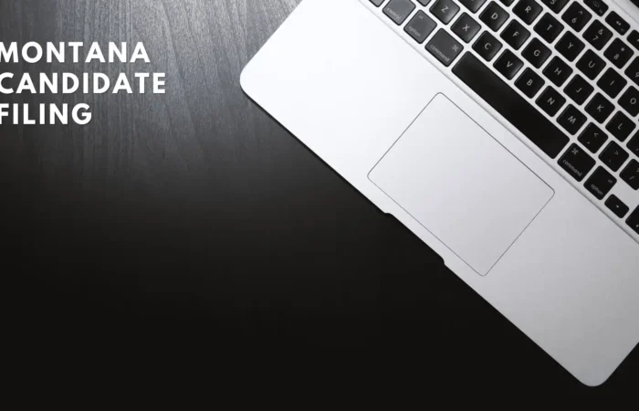 Montana Secretary of State's Office processes 154 candidate filings in first 9 days 1 A silver laptop on a dark wooden surface with the text Montana Candidate Filing in bold white letters on the left side, highlighting candidate filings for upcoming elections by the Montana Secretary of State.