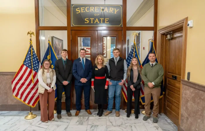 Lima students visit Montana Secretary of State's Office, State Capitol 9 A group of seven Lima students stand in a line, posing for a photo in front of the Montana Secretary of State office entrance, flanked by U.S. and state flags on both sides.