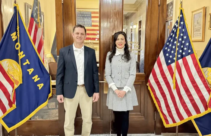 Secretary Christi Jacobsen: 'More than 20 candidate filings processed this week' 4 Two people stand side by side in front of the Secretary of State office doors, flanked by Montana state and U.S. flags on each side. The setting appears formal, with marble floors and framed items on the walls.
