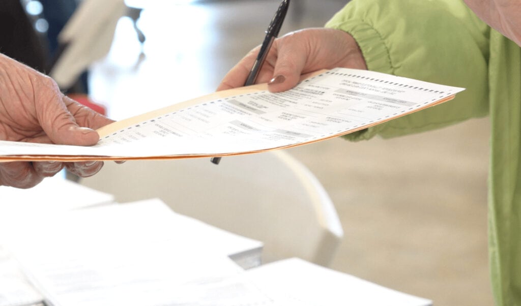 Christi Jacobsen - Montana Secretary of State 9 A voter hands in a ballot to an election official during a Montana election.