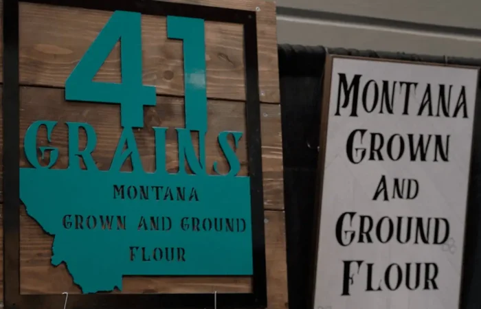 Montana Business Spotlight: 41 Grains proud to be 'Montana grown and ground' 7 Wooden and turquoise sign reads “41 Grains Montana Grown and Ground Flour,” next to a white and black sign with similar text, both displayed at an indoor booth.