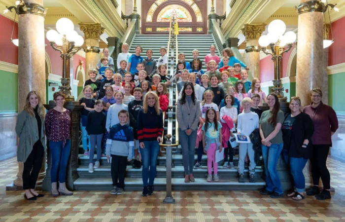 Montana City students visit Secretary of State's Office 10 Montana City students and adults pose together on the steps of an ornate building with marble columns, a patterned tile floor, and a stained-glass window during their visit with the Secretary of State.