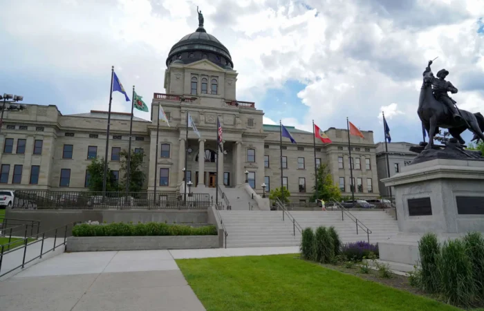 Secretary Christi Jacobsen shares Montana's new business registrations in October 2023 7 The image shows the Montana State Capitol building with its large dome, surrounded by flags and a statue of a person on horseback in the foreground—a place where Secretary Christi Jacobsen oversees new business registrations. The sky is partly cloudy.