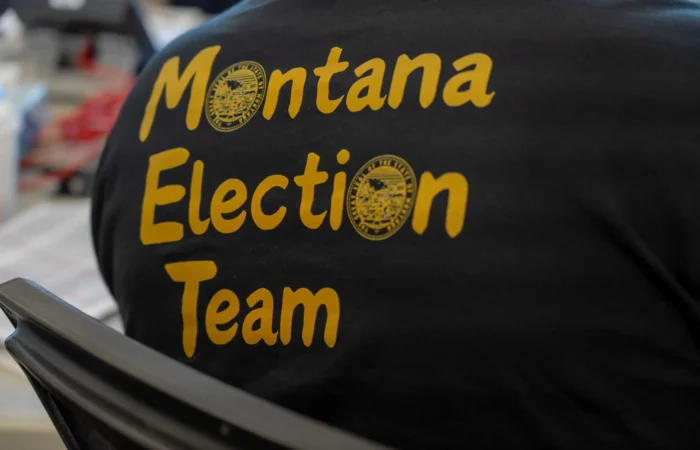 Montana's 2024 General Election is officially underway 1 A person wearing a black shirt with yellow text that reads Montana Election Team and features two official state seals, supporting Secretary of State Christi Jacobsen on Primary Election Day.