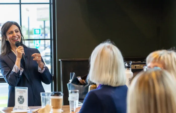 Secretary Christi Jacobsen: 'Nearly 5,000 new business registrations in February 2024' 2 A woman in a suit speaks into a microphone and smiles while addressing a small group seated at a table in a brightly lit café or restaurant.