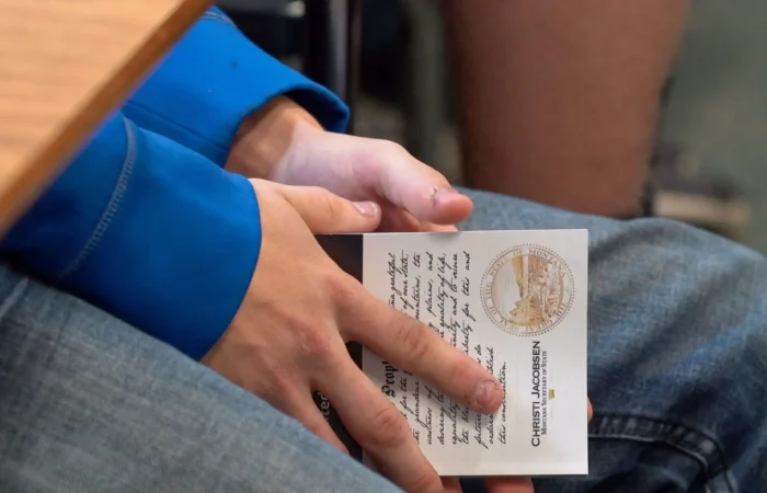 Secretary Christi Jacobsen announces winners of 2023 U.S. Constitution Contest 10 A person in blue sleeves holds a naturalization certificate on their lap, with hands clasped over the document. The lower part of another persons leg is visible nearby.