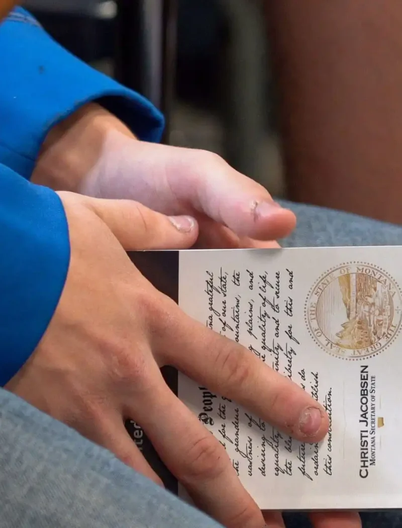 Secretary Christi Jacobsen announces winners of 2023 U.S. Constitution Contest 9 A person in blue sleeves holds a naturalization certificate on their lap, with hands clasped over the document. The lower part of another persons leg is visible nearby.