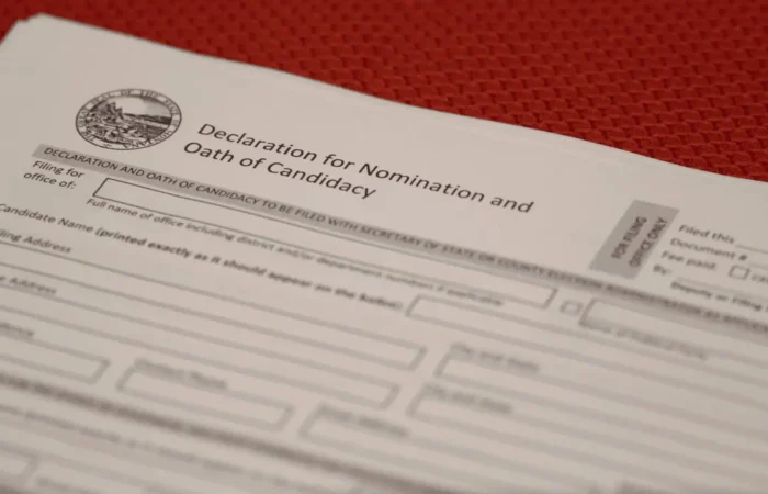 Another congressional candidate files with Montana Secretary of State's Office 4 A close-up of a “Declaration for Nomination and Oath of Candidacy” form on a red textured surface, showing blanks for candidate information and the Montana state seal—a key document for 2022 candidate filing in the election.