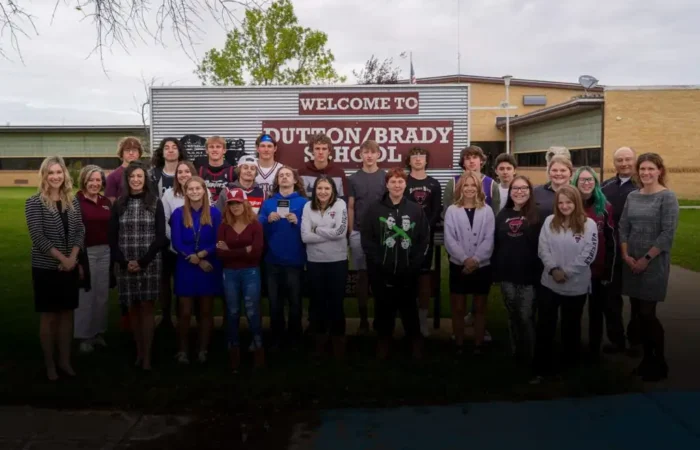 Secretary Jacobsen visits Dutton-Brady Schools, delivers Constitutions 7 A group of students and adults pose together in front of Dutton-Brady Schools, where Secretary Jacobsen delivers Constitutions. They stand on grass under a cloudy sky by a sign that reads Welcome to Dutton/Brady School.