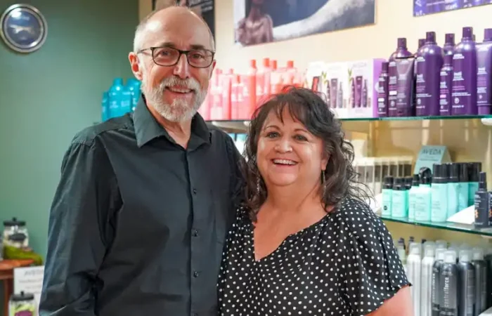 Montana Business Spotlight: Helena's Futura Lane salon exemplifies the Golden Rule 1 A smiling man and woman stand together in a salon, with shelves of colorful hair care products behind them. The man wears glasses and a black shirt, and the woman wears a black polka dot blouse.