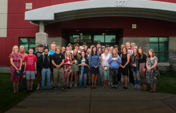 Secretary Jacobsen fulfilling campaign promise, delivers constitutions to Hamilton High School 10 A large group of Hamilton High School students and several adults, including Secretary Jacobsen, stand together outside a brick building, posing and smiling for a group photo on the sidewalk in front of glass doors.