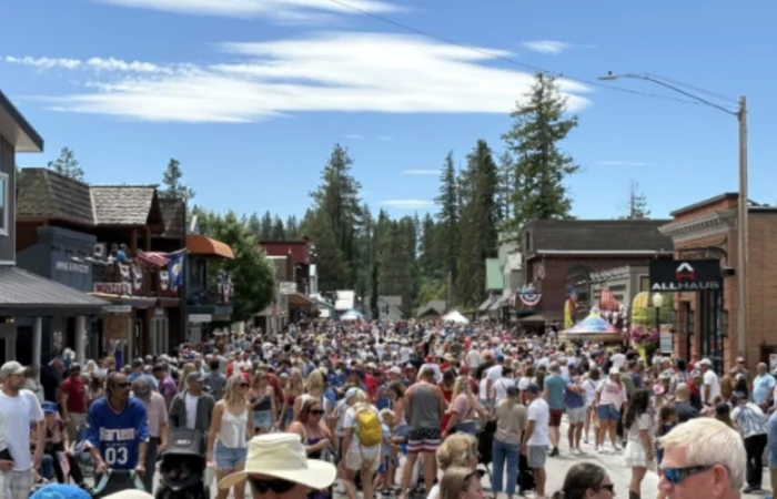 Secretary Christi Jacobsen celebrates record-breaking Montana business momentum with more than 8,000 new registrations 4 A large crowd of people fills a small town street during a sunny day, surrounded by shops and trees, with a blue sky overhead.
