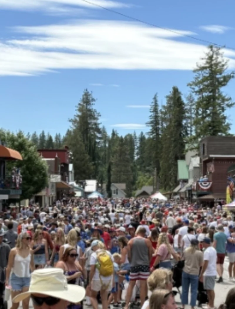 Secretary Christi Jacobsen celebrates record-breaking Montana business momentum with more than 8,000 new registrations 4 A large crowd of people fills a small town street during a sunny day, surrounded by shops and trees, with a blue sky overhead.