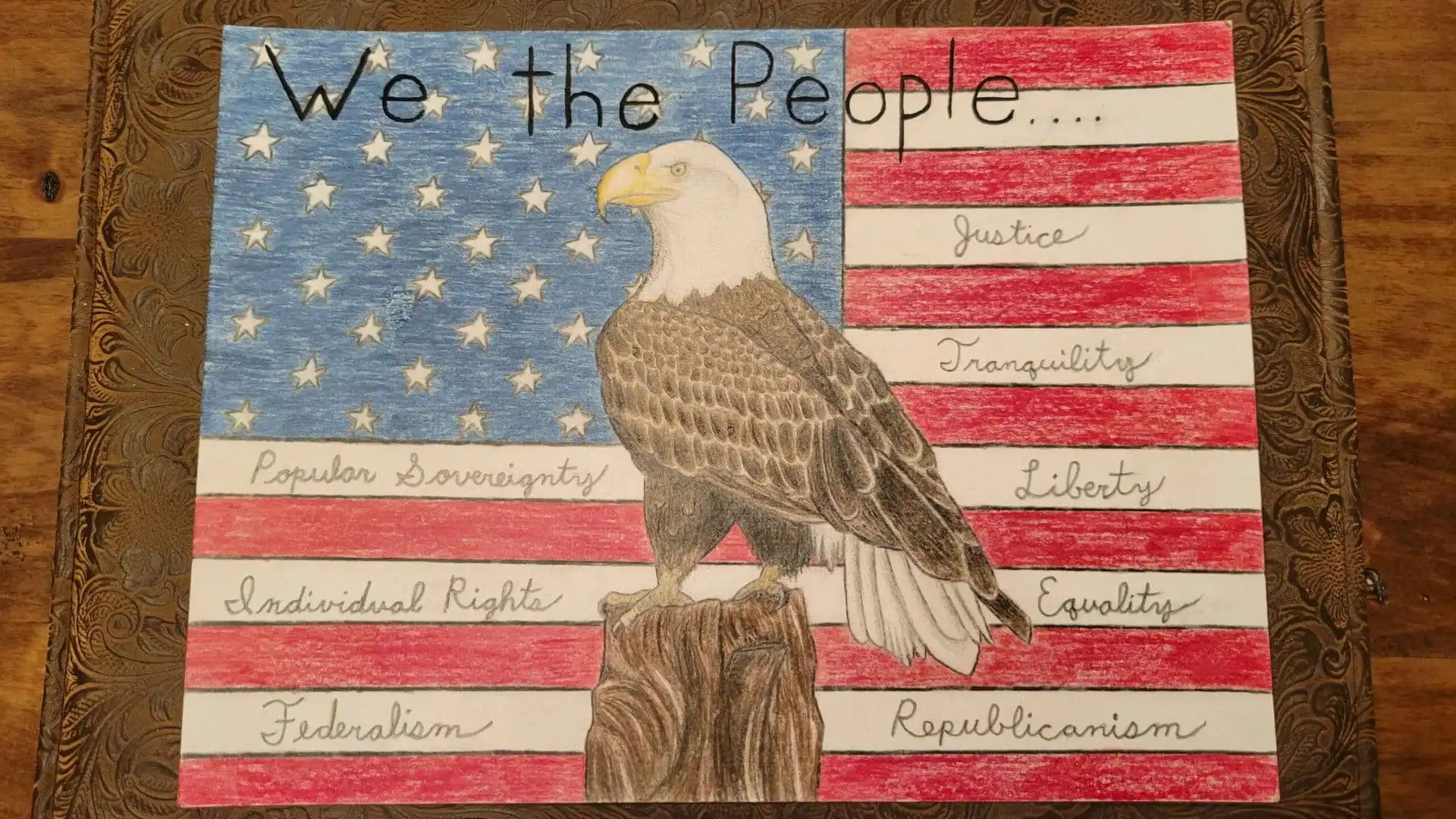 A hand-drawn American flag with a bald eagle perched on a tree stump, inspired by the US Constitution Contest. “We the People...” tops the image, with words like Justice, Liberty, and more—just as seen in 2022 winners celebrated by Christi Jacobsen.