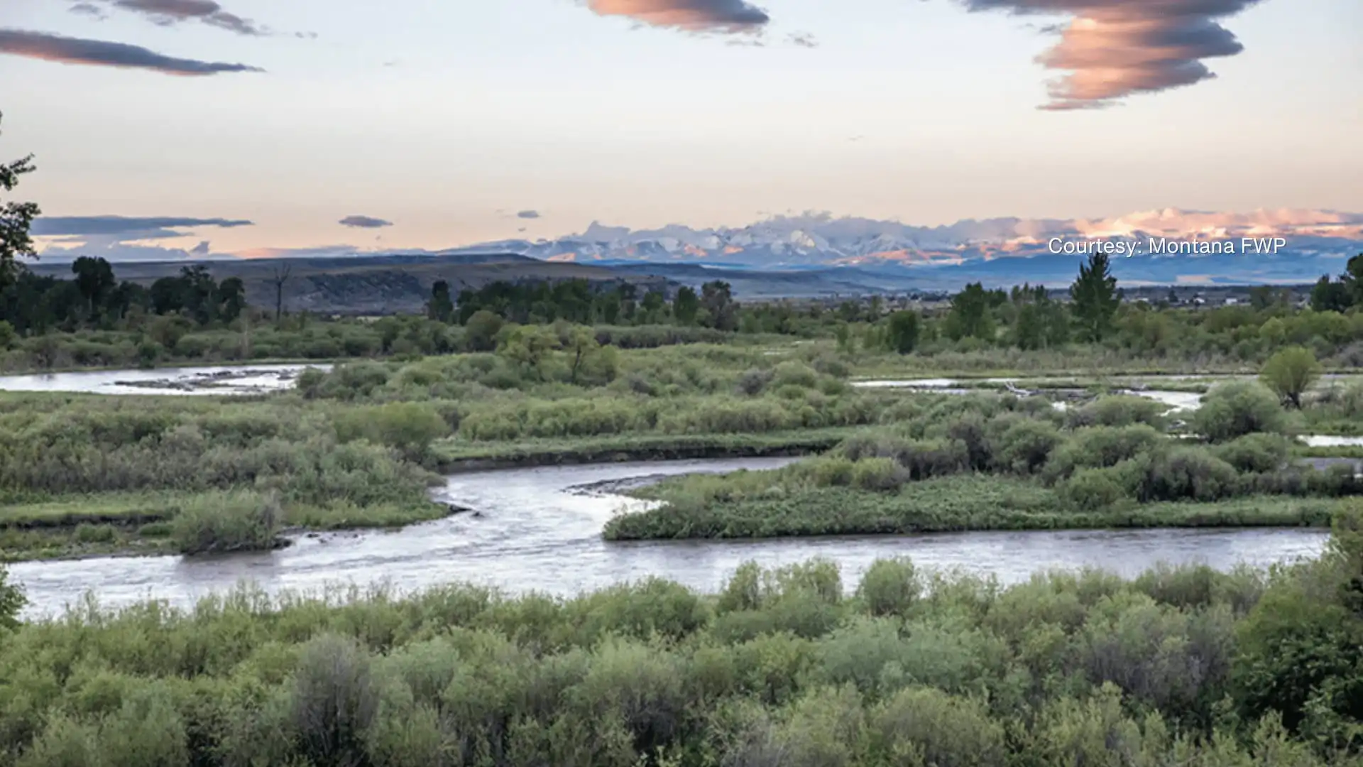 Secretary Jacobsen, Land Board approve Missouri Headwaters State Park acquisition 16 A winding river flows through lush green vegetation at Missouri Headwaters State Park, with distant mountains under a pastel-colored sunset sky—an idyllic landscape preserved through thoughtful acquisition. Clouds are scattered above the scenic view.