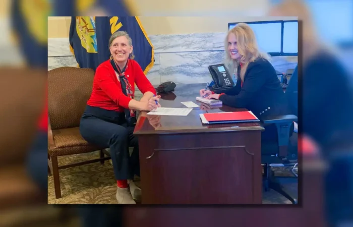 Montana's 2022 candidate filing season enters final 28 days 7 Two women sit across from each other at a wooden office desk, smiling, as papers related to the Montana 2022 candidate filing are spread out. A phone, monitor, flag, and marble wall set the backdrop in this election-focused scene.