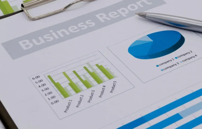 Close-up of a Montana Business economic report on a clipboard, featuring a bar chart and pie chart with product data, and a silver pen resting on the document—highlighting Secretary Jacobsens focus on data-driven insights.