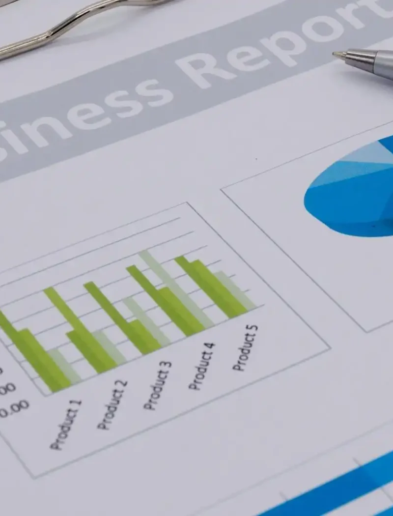 Close-up of a Montana Business economic report on a clipboard, featuring a bar chart and pie chart with product data, and a silver pen resting on the document—highlighting Secretary Jacobsens focus on data-driven insights.