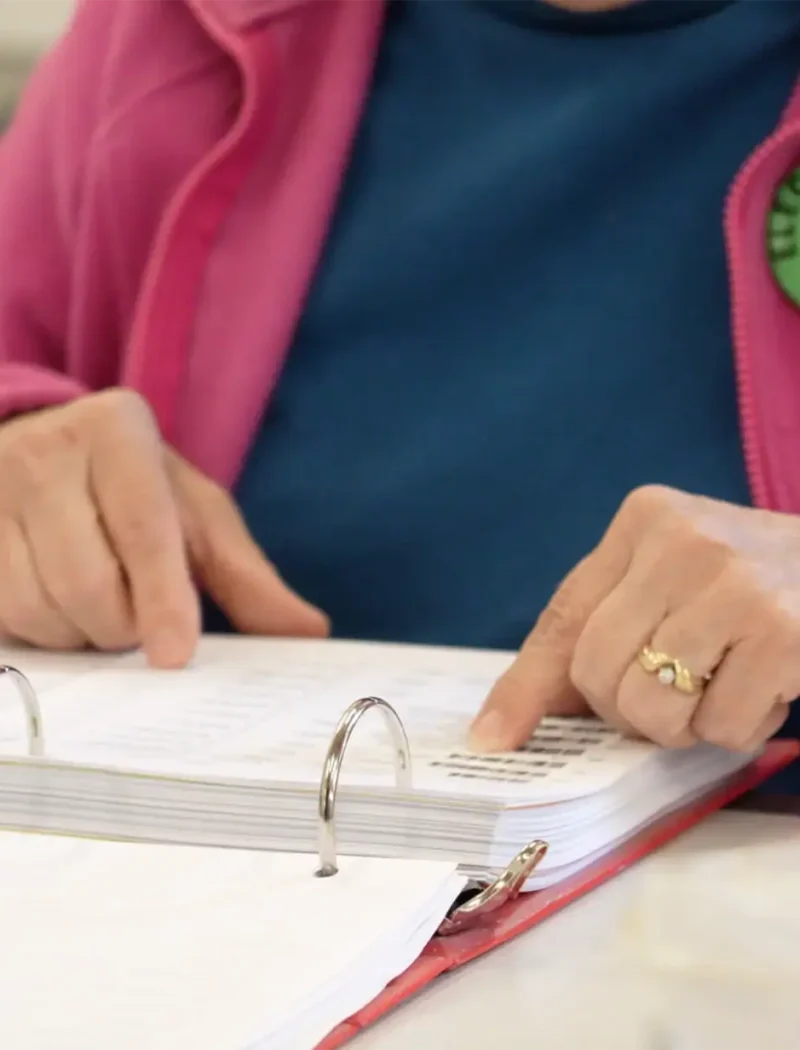 An election judge searches through the poll book to find a voter.