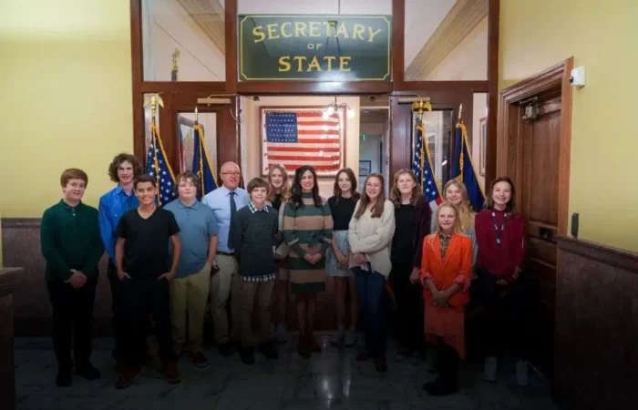Red Lodge's Roosevelt Middle School student council visits Secretary of State's Office 2 A group from Roosevelt Middle School, including student council members and adults, pose for a group photo in front of a Secretary of States Office sign and several American flags inside a government building.