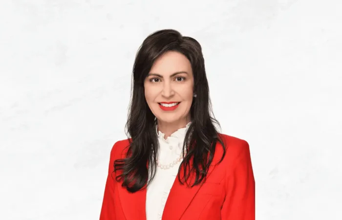 Secretary Christi Jacobsen announces more Montana business growth in June 2023 2 Woman with long dark hair wearing a red blazer, white blouse, and pearl necklace, smiling in front of a plain white background—Secretary Christi Jacobsen highlighted Montana business growth in June 2023.