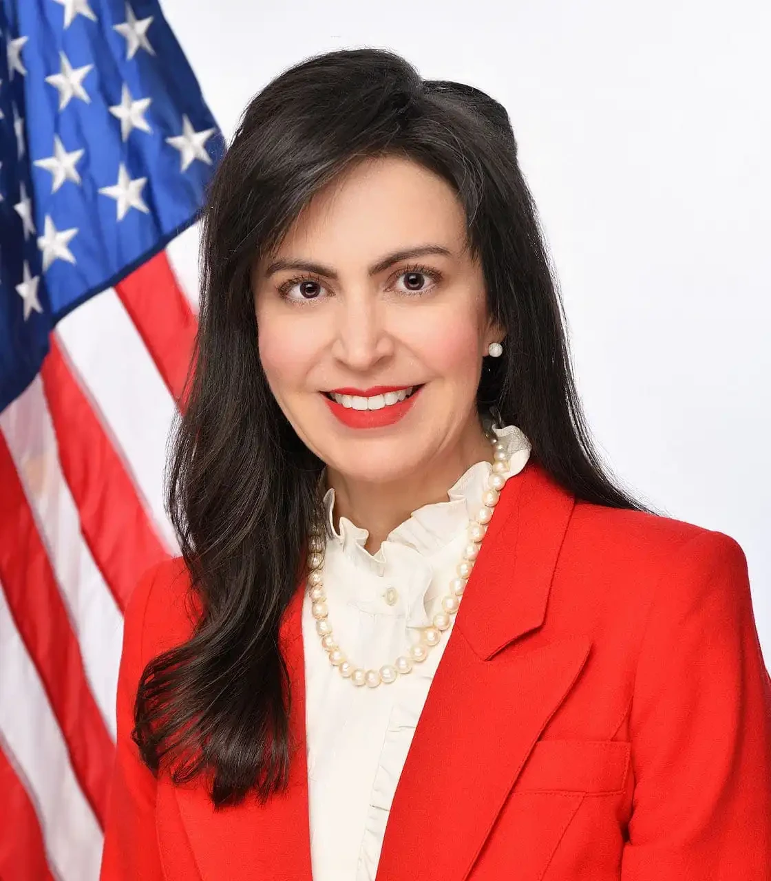 Secretary Jacobsen, in front of a U.S. flag and a white background.
