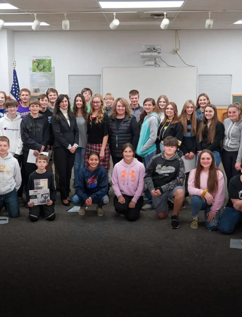 A large group of smiling teens and a few adults pose together in a Townsend Middle School classroom, standing and kneeling in rows. The background features a whiteboard, bulletin boards, and US Constitution Contest materials.