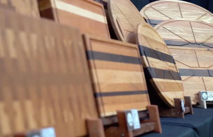 Montana Business Spotlight: Montana Block grateful for Made in Montana program 7 Several wooden cutting boards and serving trays by Montana Block, featuring unique shapes and wood patterns, are displayed upright on a black tablecloth at a craft fair as part of the Made in Montana program.