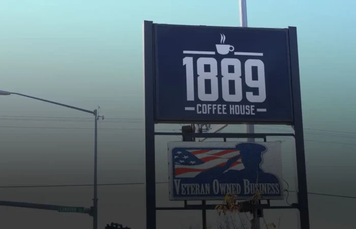Montana Business Spotlight: Veteran-owned 1889 Coffee House proud to be in Montana 2 A large outdoor sign reads 1889 Coffee House above another sign stating veteran-owned, featuring an American flag and soldier silhouette. A street sign for Laramie St. appears in the background of this Montana business.