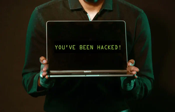 Secretary of State's Office takes part in Cybersecurity Awareness Month 4 A person in a dark shirt holds a laptop, with the screen displaying the message YOUVE BEEN HACKED! in green text on a black background.